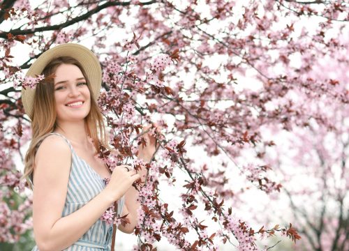 Beautiful young woman near blossoming tree on spring day