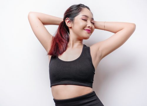 Smiling sporty Asian woman wearing sportswear is relaxing after working out