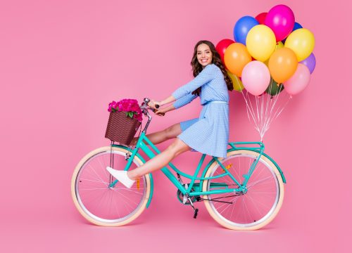 Full length body size profile side view of attractive cheerful wavy-haired lady riding bike