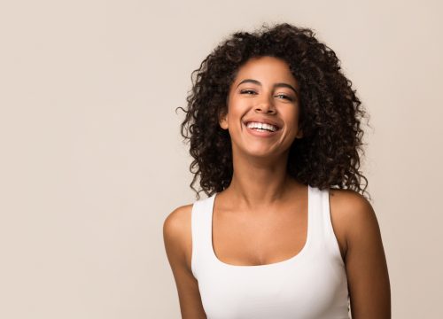 Portrait of laughing young woman standing against light background