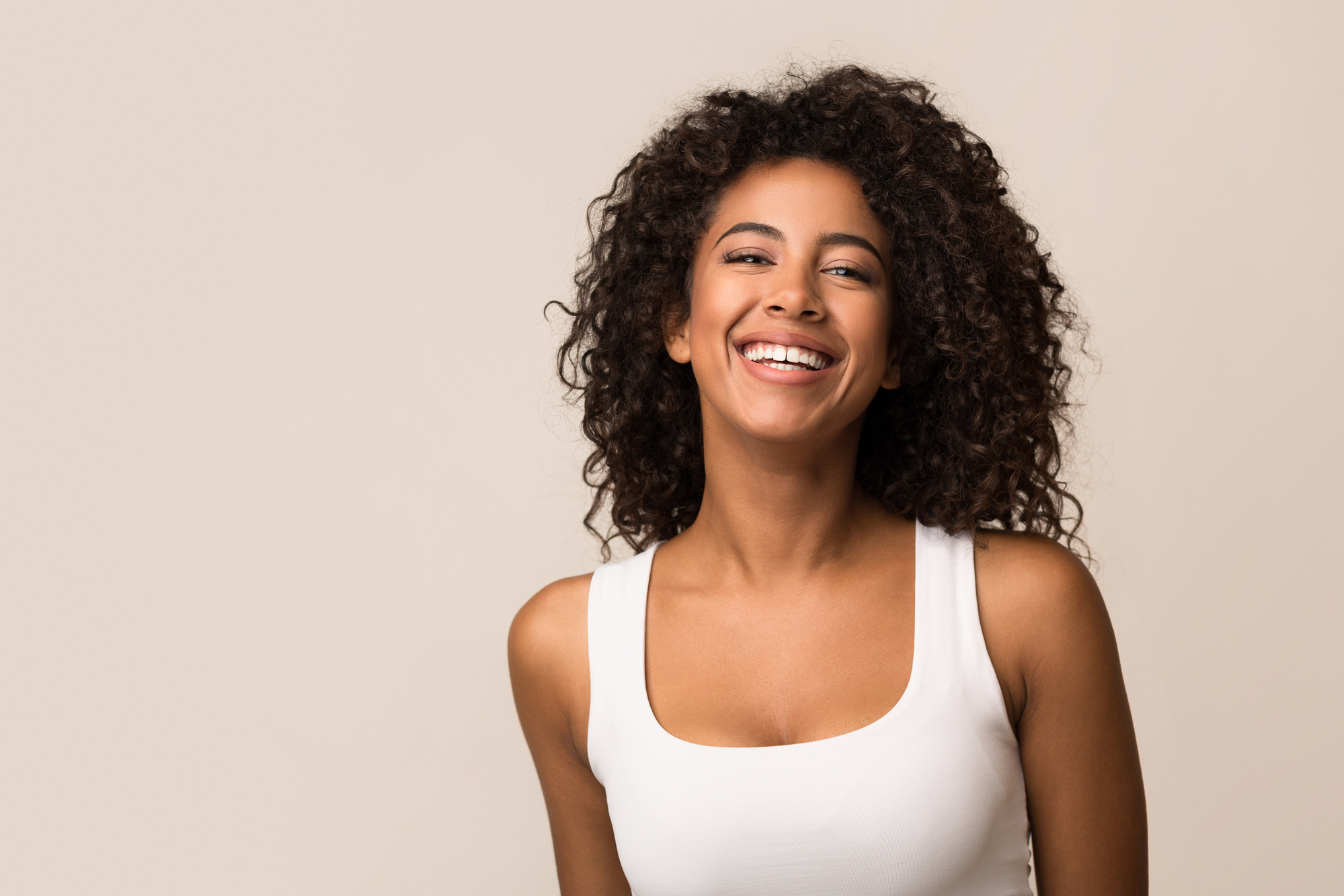 Portrait of laughing young woman standing against light background