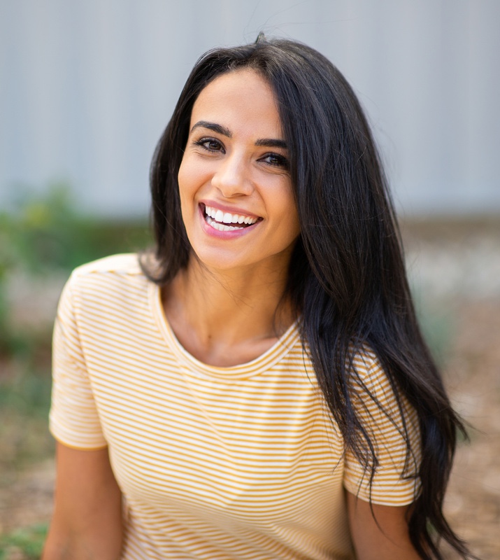 Close up portrait smiling young hispanic woman sitting outdoors